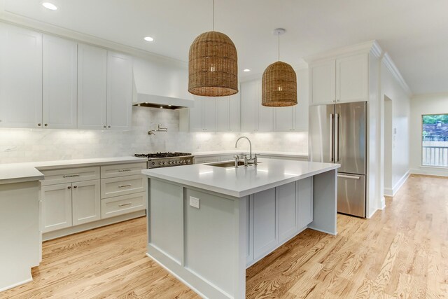 kitchen featuring custom range hood, tasteful backsplash, light countertops, a sink, and high quality fridge