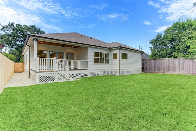 back of house with ceiling fan, a fenced backyard, a lawn, a shingled roof, and a deck