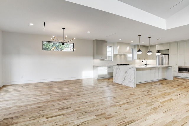 kitchen with custom range hood, a healthy amount of sunlight, light wood-type flooring, and appliances with stainless steel finishes