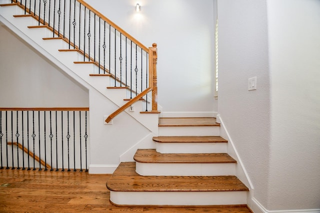 stairway with wood finished floors and baseboards