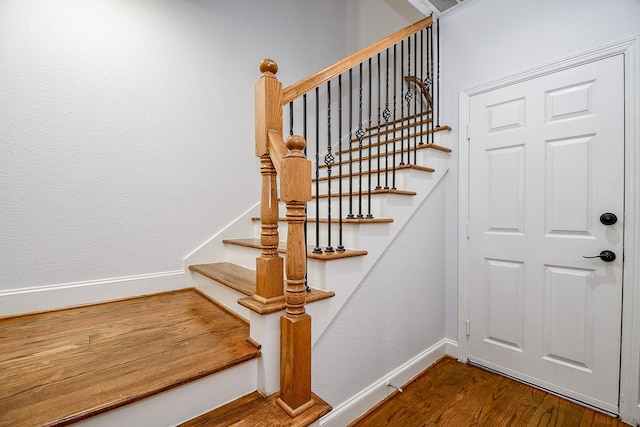 staircase with baseboards and wood finished floors