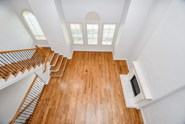 unfurnished living room featuring wood finished floors, a high ceiling, baseboards, and stairs