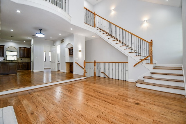 unfurnished living room with wood finished floors, a sink, baseboards, and recessed lighting