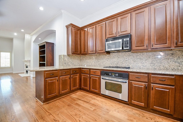 kitchen with crown molding, light wood-type flooring, a peninsula, appliances with stainless steel finishes, and backsplash