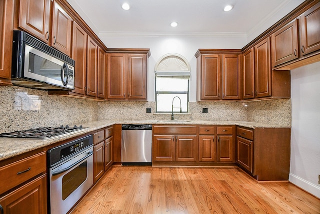 kitchen with light stone countertops, light wood-style floors, a sink, and appliances with stainless steel finishes