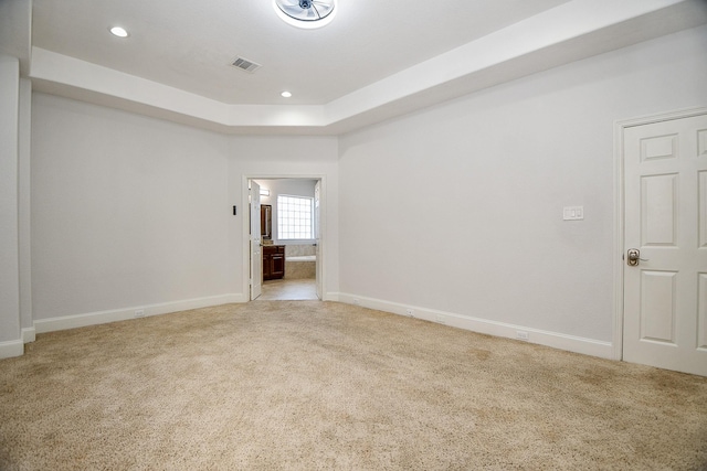 empty room with visible vents, baseboards, a tray ceiling, recessed lighting, and light carpet