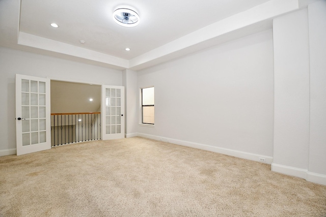 spare room with a raised ceiling, french doors, and carpet floors