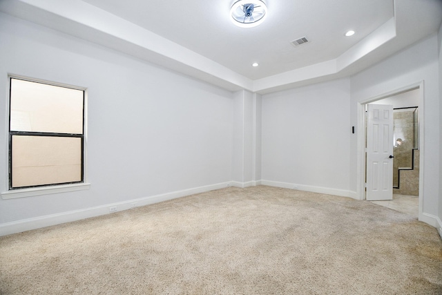 empty room with visible vents, baseboards, a tray ceiling, carpet floors, and recessed lighting