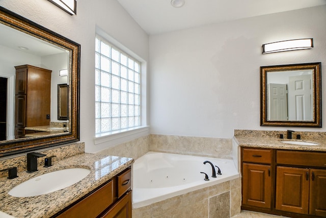 full bathroom with a jetted tub, two vanities, and a sink