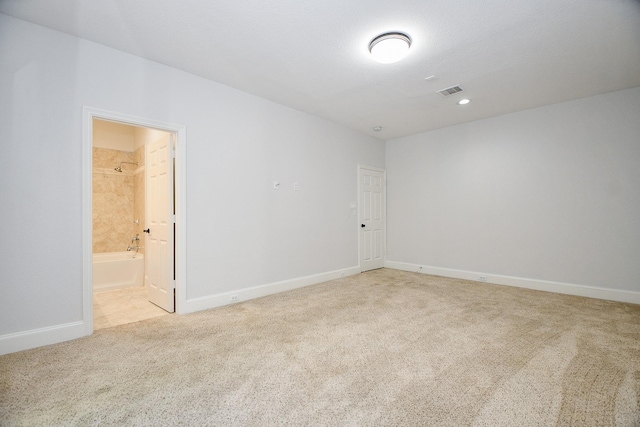 spare room featuring light carpet, visible vents, and baseboards