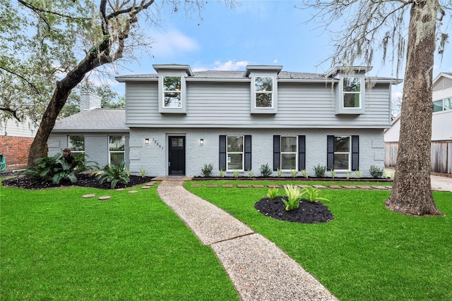 view of front of house with fence, brick siding, a chimney, and a front lawn
