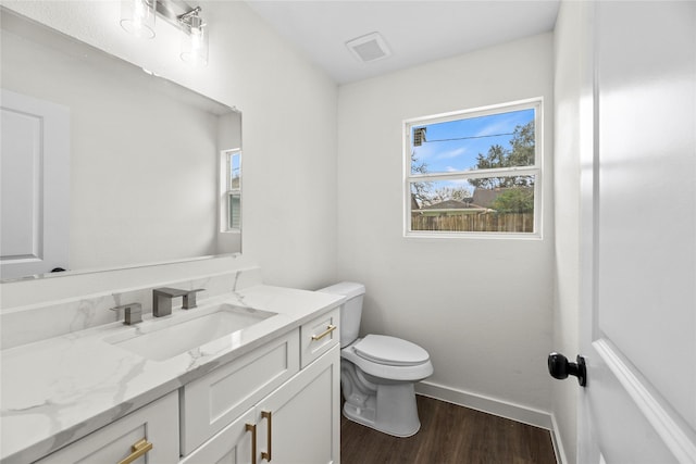 bathroom with visible vents, baseboards, toilet, vanity, and wood finished floors