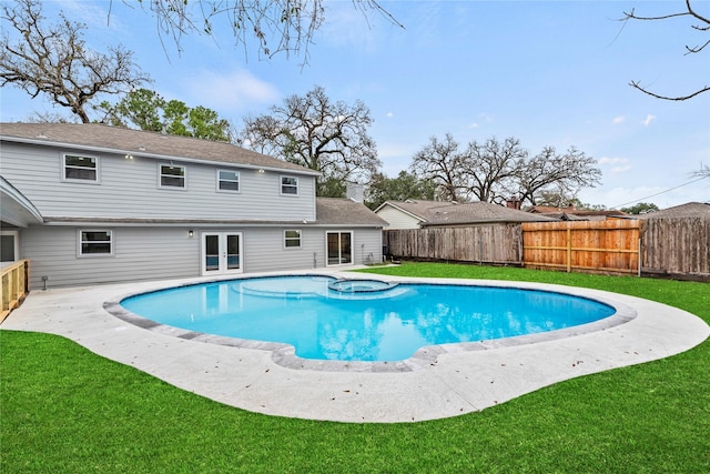 view of swimming pool with french doors, a patio area, a fenced backyard, a pool with connected hot tub, and a lawn