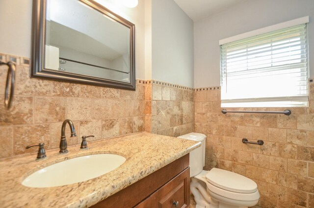 6606 Flamingo Dr, Houston, TX 77087 - bathroom with toilet, vanity, a wainscoted wall, and tile walls