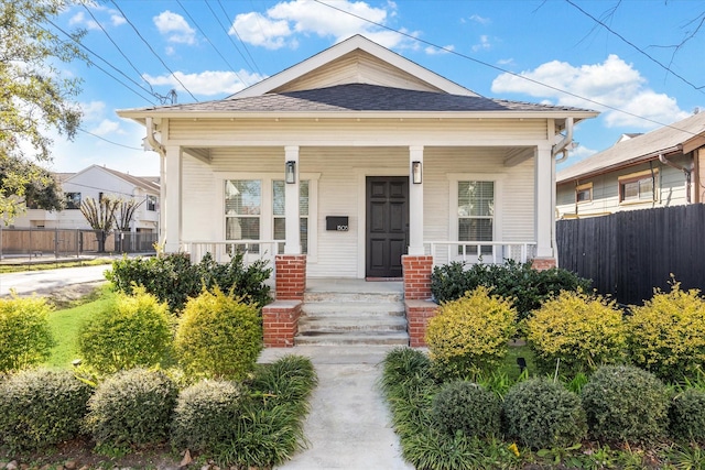 1505 Bonner St, Houston, TX 77007 - view of front facade with a porch, a shingled roof, fence, and brick siding