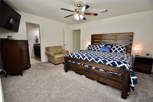 bedroom featuring light carpet, a ceiling fan, and ensuite bathroom