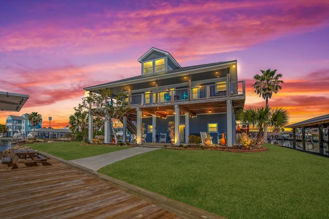 back of property at dusk with a balcony and a lawn