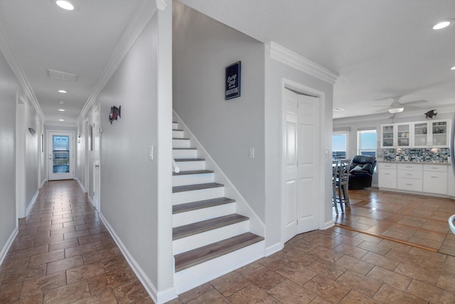corridor featuring crown molding, stone tile flooring, baseboards, and recessed lighting