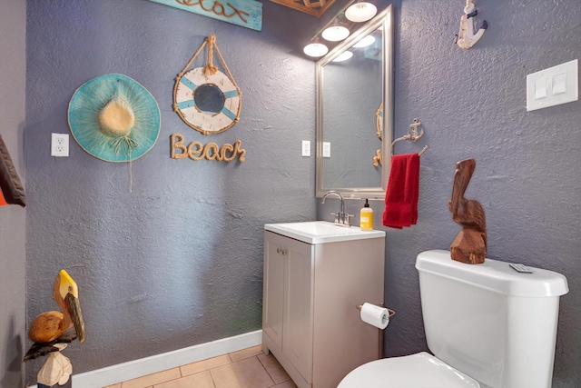 half bath with tile patterned floors, vanity, baseboards, and toilet