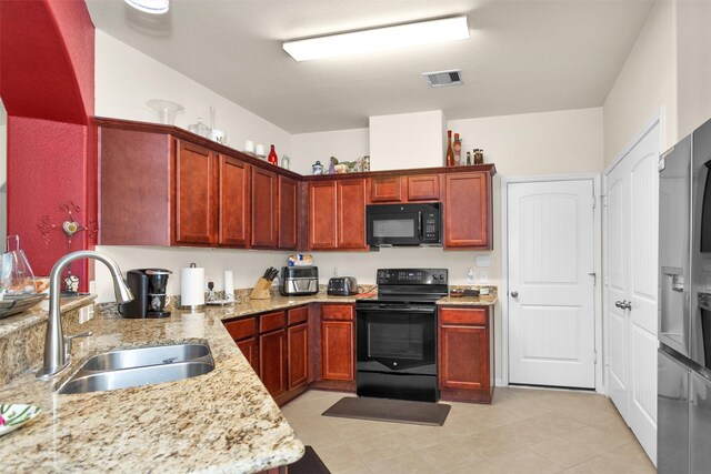 5305 Weeping Bow, Willis, TX 77378 - kitchen featuring black appliances, light stone countertops, visible vents, a sink, and reddish brown cabinets