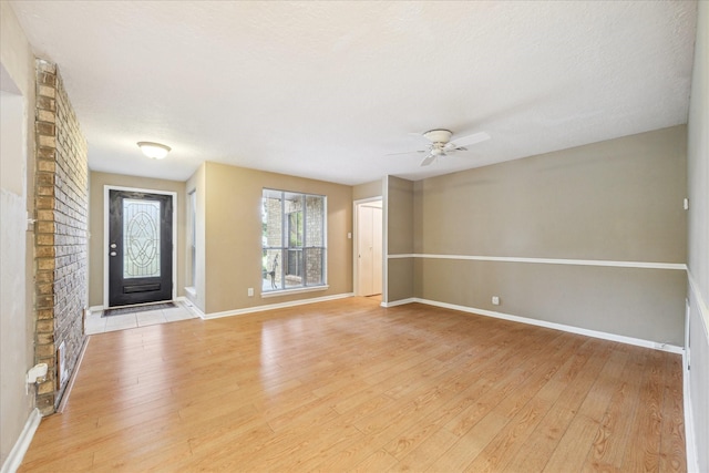 interior space featuring light wood-type flooring, a ceiling fan, and baseboards
