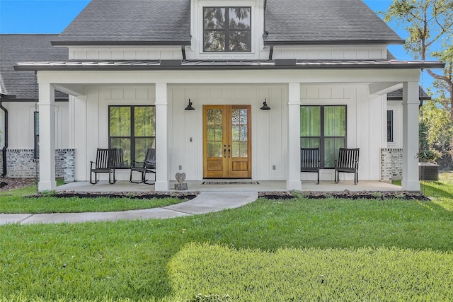 rear view of property featuring french doors, roof with shingles, a porch, a lawn, and board and batten siding