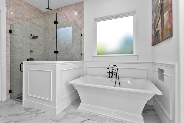 full bath featuring a freestanding tub, marble finish floor, a decorative wall, and a stall shower
