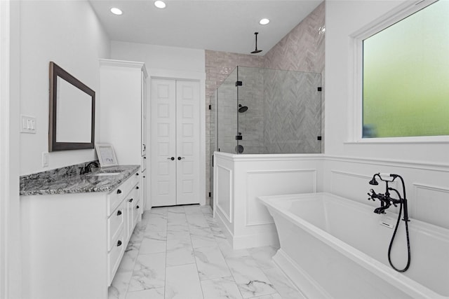 bathroom featuring recessed lighting, marble finish floor, a freestanding tub, a shower stall, and vanity
