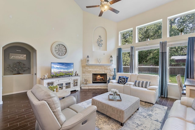 living room featuring baseboards, a towering ceiling, a ceiling fan, and wood finish floors