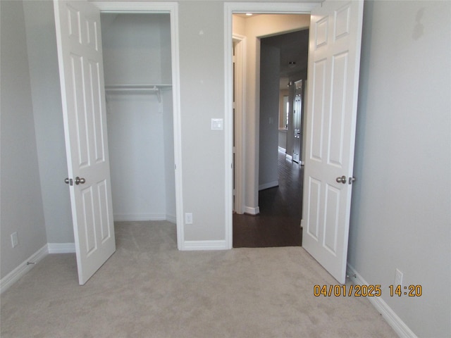 unfurnished bedroom with a closet, baseboards, and carpet flooring