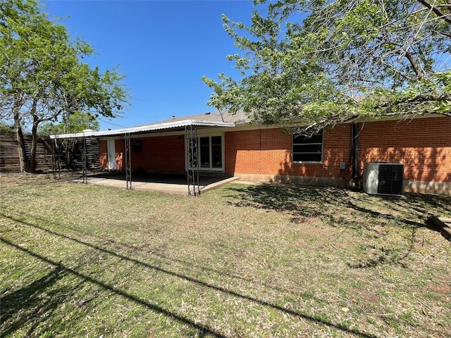 rear view of property with a patio area, brick siding, central air condition unit, and a lawn