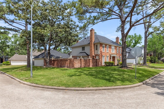 view of front of home featuring brick siding, a front yard, and a chimney