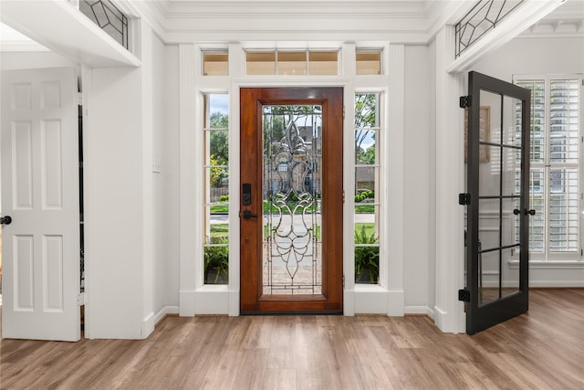 foyer with wood finished floors, plenty of natural light, baseboards, ornamental molding, and french doors