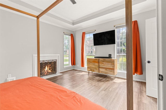 unfurnished bedroom featuring crown molding, wood finished floors, a lit fireplace, and baseboards