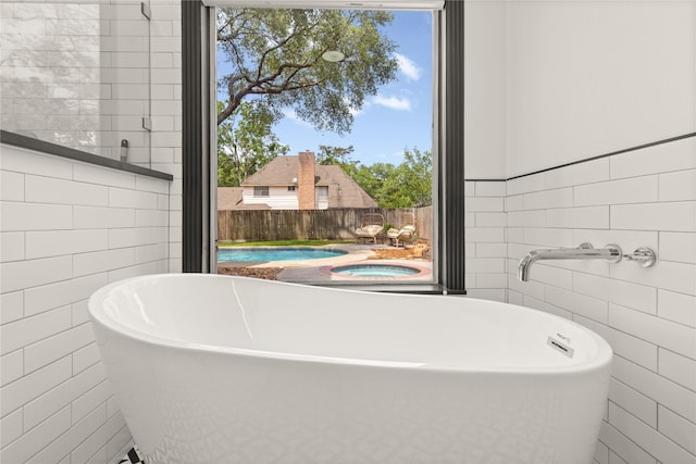 bathroom with tile walls and a freestanding bath