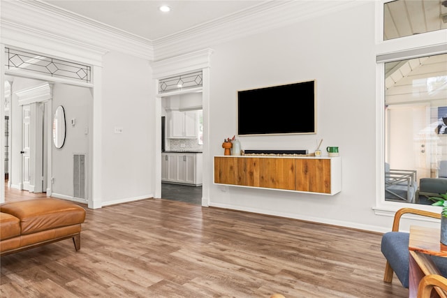 living room featuring wood finished floors, ornamental molding, baseboards, and recessed lighting