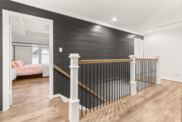 hallway featuring attic access, an upstairs landing, crown molding, wood finished floors, and baseboards