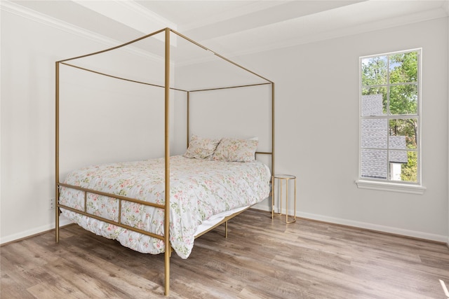 bedroom with crown molding, wood finished floors, multiple windows, and baseboards