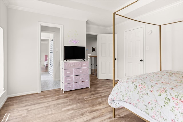 bedroom with light wood finished floors, crown molding, baseboards, and a closet