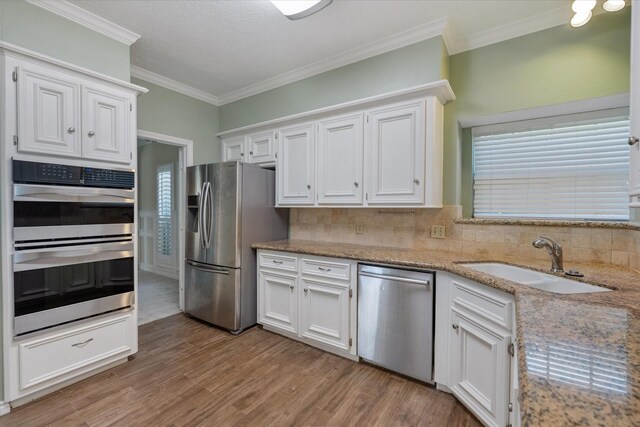 7914 Rio Crystal Dr, Houston, TX 77095 - kitchen with appliances with stainless steel finishes, decorative backsplash, a sink, white cabinetry, and ornamental molding