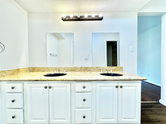 7914 Oakington Dr, Houston, TX 77071 - full bathroom with wood finished floors, a textured ceiling, double vanity, and a textured wall