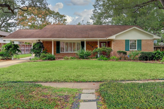 ranch-style home featuring driveway, brick siding, fence, a front yard, and a carport