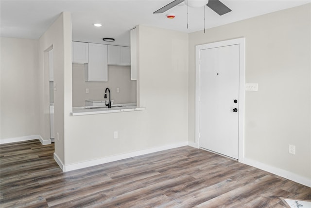 kitchen with light countertops, ceiling fan, white cabinetry, and wood finished floors