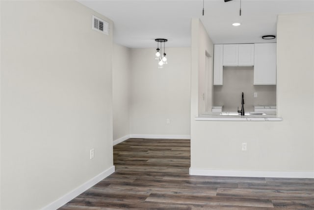 kitchen with visible vents, white cabinets, baseboards, a sink, and dark wood finished floors
