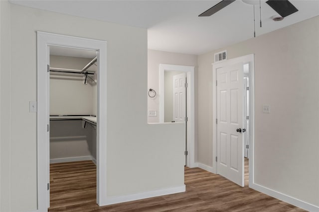 interior space featuring a closet, baseboards, visible vents, ceiling fan, and wood finished floors