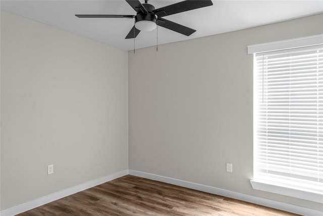 empty room with dark wood-style floors, baseboards, a ceiling fan, and a wealth of natural light