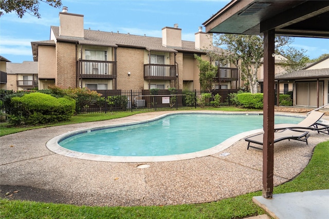 pool with a patio area, central AC unit, and fence