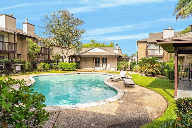 community pool with a patio area and fence