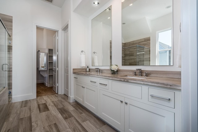 8624 Emnora Ln, Houston, TX 77080 - bathroom featuring a stall shower, double vanity, a walk in closet, baseboards, and wood finished floors