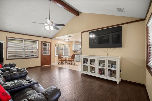 living area with ceiling fan, lofted ceiling with beams, wood finished floors, and baseboards